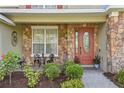 Inviting front porch with stone detail, quaint seating, and a decorative glass front door at 1065 Cavan Dr, Apopka, FL 32703