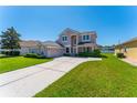 Charming two-story home featuring a well-manicured lawn, lush landscaping, and neutral color palette at 2340 Hinsdale Dr, Kissimmee, FL 34741