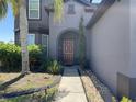 Inviting front entrance with an arched doorway and well-maintained landscaping at 2865 Running Brook Cir, Kissimmee, FL 34744