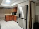 Open kitchen with granite counters, wood cabinets, stainless fridge, and tile floors at 4838 Pebble Beach Dr # A, Orlando, FL 32811