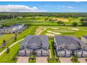 Aerial shot of modern townhomes with a view of the adjacent golf course, vibrant greenery, and partly cloudy sky at 507 Ocean Course Ave # 507, Davenport, FL 33896