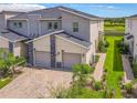 Modern townhome with two-car garage, stone accents, brick driveway, and landscaping; golf course in the background at 507 Ocean Course Ave # 507, Davenport, FL 33896