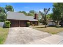 Inviting home with a spacious driveway, mature trees, and classic architecture at 825 Mellowood Ave, Orlando, FL 32825