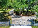 Gated driveway leading to a beautiful white home surrounded by a lush landscape of trees at 1155 Taylor E Rd, Deland, FL 32724