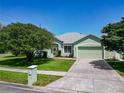 Beautiful home showcasing a lush green lawn, mature trees, and a concrete driveway leading to a two-car garage at 1157 Valley Creek Run, Winter Park, FL 32792