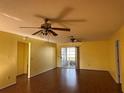 Spacious living room featuring hardwood floors, ceiling fans, and access to the lanai at 1705 Betrillo Ct, The Villages, FL 32162