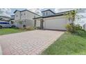 Paver driveway leading to a well-maintained two-story home with stone accents at 2412 Gold Dust Dr, Clermont, FL 34715