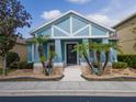 Charming blue single-Gathering home with a well-manicured front yard and inviting entryway with palm trees at 306 Balfour Dr, Winter Springs, FL 32708