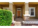 Inviting front porch featuring stone accents, a modern light fixture, and a beautiful wood door at 3281 Pawleys N Loop, St Cloud, FL 34769