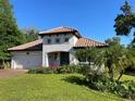 Charming home with a tile roof, manicured lawn, and vibrant flower beds under a clear, sunny sky at 3609 Azurite Ct, Deland, FL 32724