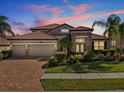 Beautiful home with a tile roof, brick driveway and tropical landscaping in the front yard at sunset at 1945 Via Lago Dr, Lakeland, FL 33810