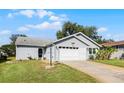 Quaint single-story home with an attached two-car garage, green lawn, and light-blue siding at 32537 Oak Park Dr, Leesburg, FL 34748