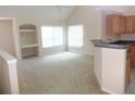 Open living area with built in desk/shelving, neutral carpet, and breakfast bar to the kitchen area at 3364 Westchester Square Blvd # 204, Orlando, FL 32835