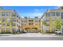 Beautifully landscaped yellow condominium building with palm trees, and breezeway for parking at 860 N Orange Ave # 226, Orlando, FL 32801