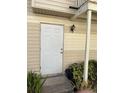 Close up of front door to condo unit showcasing outdoor lighting, building materials, and landscaping at 1001 Spring Meadow # 1001, Kissimmee, FL 34741