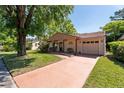 Charming single-story home features a terracotta roof, attached garage, and a lush front yard with mature trees at 10423 Manassas Cir, Orlando, FL 32821