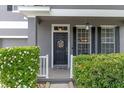 Close-up of the front door with decorative wreath, sidelights, and manicured hedges at 10435 Eastpark Lake Dr, Orlando, FL 32832