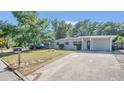 Neat home exterior with a well-maintained lawn, mature trees, and a long driveway at 132 W Lauren Ct, Casselberry, FL 32730