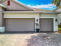 Spacious three-car garage featuring paneled doors and a brick paver driveway at 14001 Jomatt Loop, Winter Garden, FL 34787