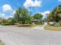 Well-maintained front yard with a mature tree, a long driveway, and partial view of the cozy home at 1821 Goodrich Ave, Winter Park, FL 32789