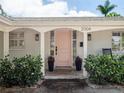 Close-up of a charming entrance featuring a pink front door, potted plants, and stylish exterior lighting at 2004 Mohawk Trl, Maitland, FL 32751