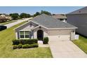 Inviting single-Gathering home featuring lush green lawn, symmetrical landscaping, and a neutral color palette at 3702 Maidencain St, Clermont, FL 34714