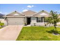 Well-maintained single-Gathering home featuring manicured lawn, gray exterior, attached garage, and classic architectural details at 445 Auburn Grove Pl, Auburndale, FL 33823