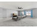 Cozy living room featuring a comfortable sectional sofa, large windows, and a ceiling fan at 445 Auburn Grove Pl, Auburndale, FL 33823