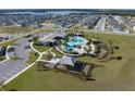 Aerial view of community amenities featuring a pool, clubhouse, and playground amidst lush landscaping at 7138 Rolling Leaf Rd, Groveland, FL 34736