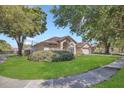 Traditional home showcasing a well-kept lawn, mature trees, and a welcoming facade with an attached garage at 8061 Bangle Ln, Orlando, FL 32836