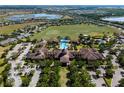 Aerial view showcases the community clubhouse, pool, tennis courts, and surrounding residences and green space at 115 Crescent Moon Dr, Groveland, FL 34736