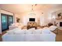 Bright living room featuring white sofas, a modern chandelier, and a painted brick fireplace at 1651 Big Oak Ln, Kissimmee, FL 34746