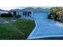 A tidy home features a freshly sodded lawn, a stamped concrete driveway, and an attached garage, all in a single-story design at 1805 San Luis Ln, The Villages, FL 32159