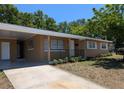 Inviting single-story home featuring a cozy porch, landscaping, and a convenient covered carport at 2013 Sarazen Ct, Orlando, FL 32808