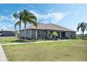 Gray home featuring a well-manicured lawn, inviting front porch with rocking chairs, and mature palm trees at 4400 Walker Lake Rd, Bartow, FL 33830