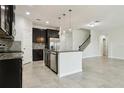 Stylish kitchen boasts granite counters, stainless appliances, dark cabinetry, mosaic backsplash, and an island overlooking living area at 611 Marsh Reed Dr, Winter Garden, FL 34787