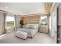 Relaxing main bedroom featuring a tray ceiling, plush carpet, ensuite bathroom, and lots of natural light at 6635 Lullaby Way, Mascotte, FL 34753
