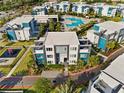 Aerial view of condo community featuring modern architecture, a playground, swimming pool, and lush landscaping at 7770 Sandy Ridge Dr # 207, Reunion, FL 34747