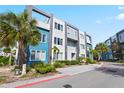 Modern three-story building with a blue and grey exterior surrounded by small palm trees and manicured landscaping at 7770 Sandy Ridge Dr # 207, Reunion, FL 34747