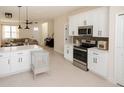 Modern kitchen with white cabinets, stainless steel appliances, and an open view into the living area at 900 S Maple Ave, Sanford, FL 32771
