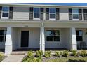 Front exterior view of a two-story townhome, showcasing a covered porch with white columns at 15098 Windflower Aly, Winter Garden, FL 34787