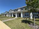 View of a two-story townhome exterior with a covered porch, landscaped front yard, and brick walkway at 15098 Windflower Aly, Winter Garden, FL 34787