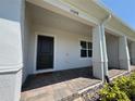 Close-up of a covered front porch with brick pavers, a dark front door, and a 