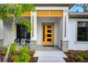 Contemporary home entrance with yellow door, stone accents, modern lighting, and curated landscaping at 18026 Reynolds Pkwy, Orlando, FL 32833