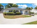 Charming single-story home with a well-manicured lawn, lush green bushes, and a blue front door at 2812 E Michigan St, Orlando, FL 32806