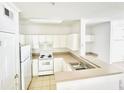 A well-lit kitchen with white cabinets and appliances with an adjacent bar that looks into the living room at 315 Grand Magnolia Ave # 112, Celebration, FL 34747