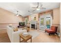 Cozy living room with a fireplace, ceiling fans, light wood floors, and a sliding glass door to the patio at 4371 Vestawood Ct, Sanford, FL 32773
