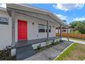 Inviting front porch features a bright red door, stylish gray accents, and a well-maintained walkway at 5612 Meridian Way, Orlando, FL 32808