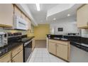 Well-lit kitchen with black countertops, light wood cabinets, and stainless steel appliances at 725 Crest Pines Dr # 422, Orlando, FL 32828
