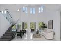 Bright and airy living room with soaring ceilings, glass staircase, and sleek, modern furniture at 10849 Emerald Chase Dr, Orlando, FL 32836